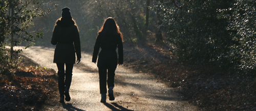 Photo of two women walking on a wooded trail